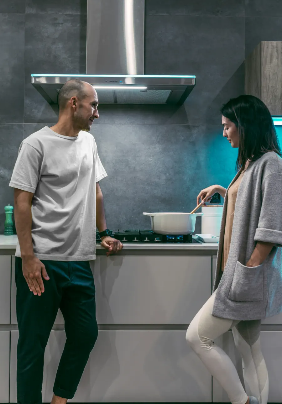 A couple talking in a modern kitchen with a gas hob and extractor